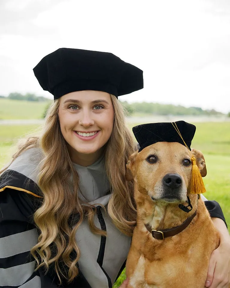 Dr. Gracie Linam in her graduation cap and gown with her dog